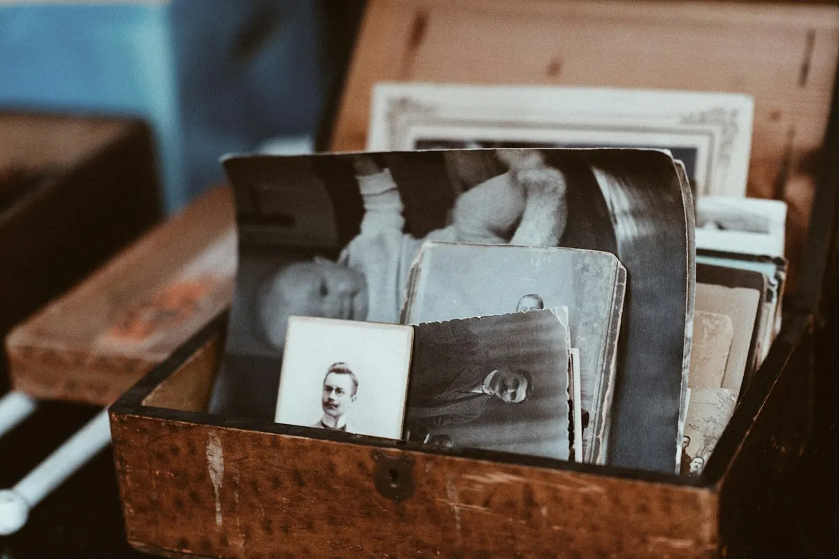 Old family photos stacked in a wooden box.