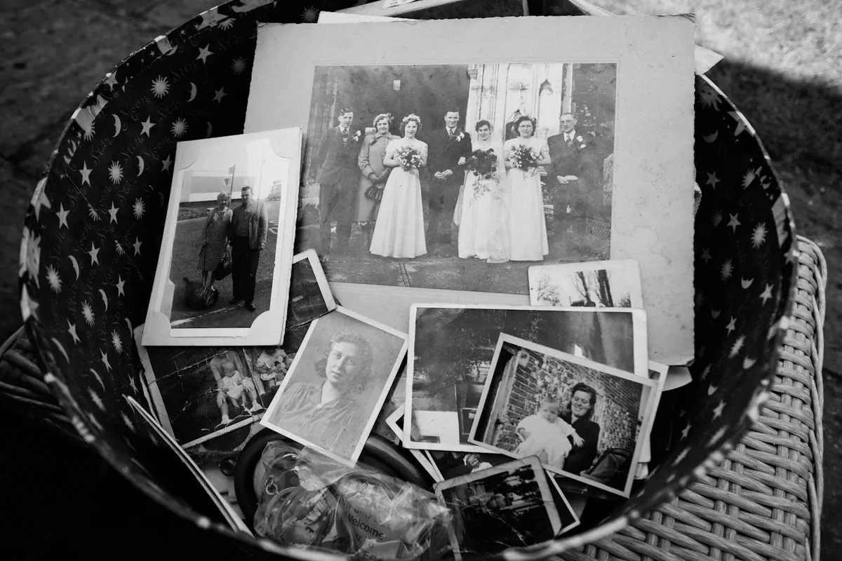 Old black and white photos in a basket, with a wedding photo on top.