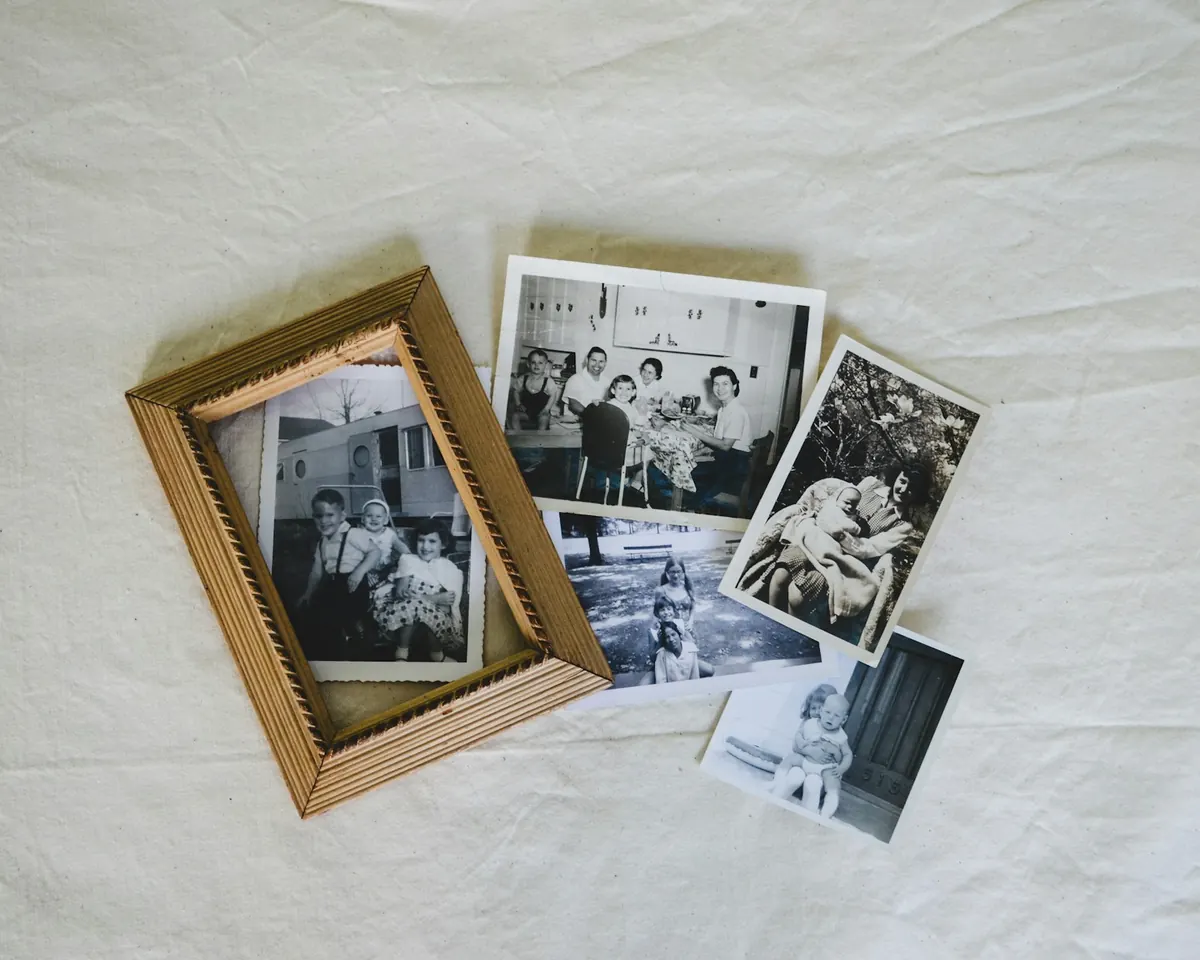 Old family photos and a framed print spread out on a sheet.